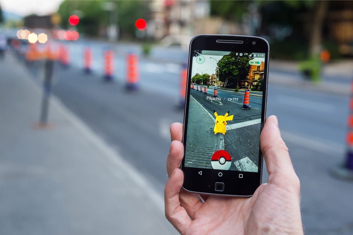 man playing with immersive technology augmented reality app pokemon go on the street