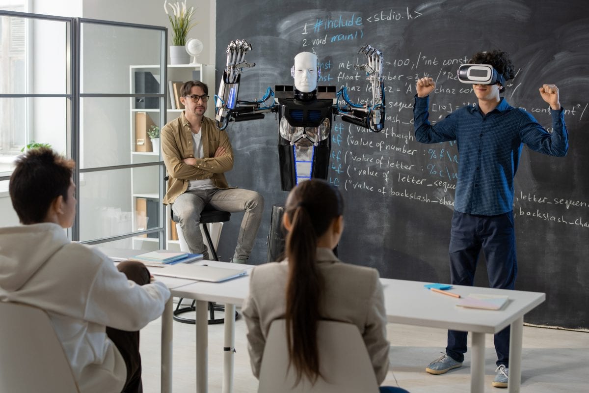 Student with VR headset demonstrating abilities of automation robot in front of his classmates during presentation